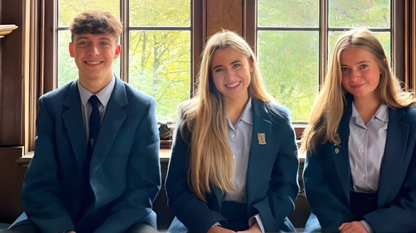 Drei Schüler der Lomond School stehen vor einem großen Fenster mit Blick auf Bäume und Grünfläche.