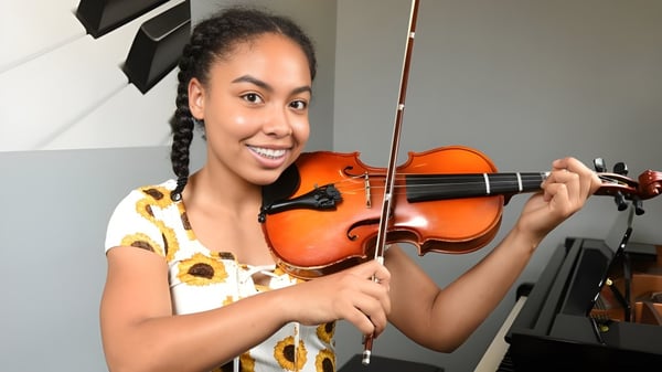 Eine Schülerin der London Central Secondary School spielt Violine in einem Raum mit Musikinstrumenten im Hintergrund.