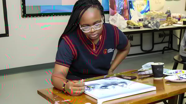 Eine Schülerin der London International Academy sitzt konzentriert an einem Tisch und arbeitet an einem Kunstwerk.