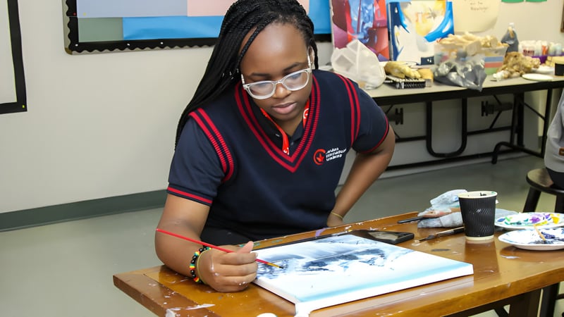 Eine Schülerin der London International Academy sitzt konzentriert an einem Tisch und arbeitet an einem Kunstwerk.