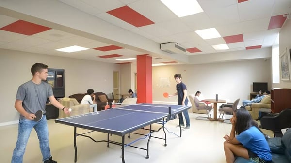 Schüler der London International Academy spielen Tischtennis in einem hellen Raum mit roten Wandakzenten.