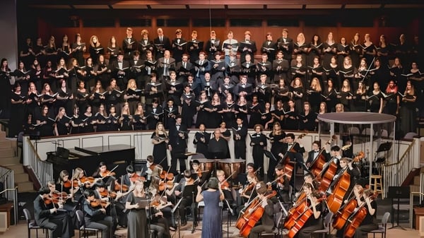 Der Chor und das Orchester des London South Collegiate Institute treten gemeinsam auf einer Bühne auf.