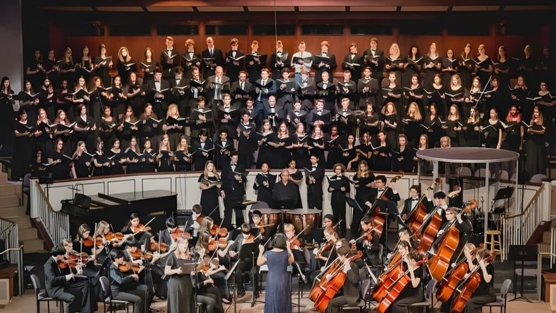 Der Chor und das Orchester des London South Collegiate Institute treten gemeinsam auf einer Bühne auf.