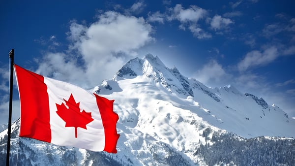 Ein schneebedeckter Berggipfel mit einer wehenden kanadischen Flagge vor klarem Himmel auf dem Gelände des London South Collegiate Institute.