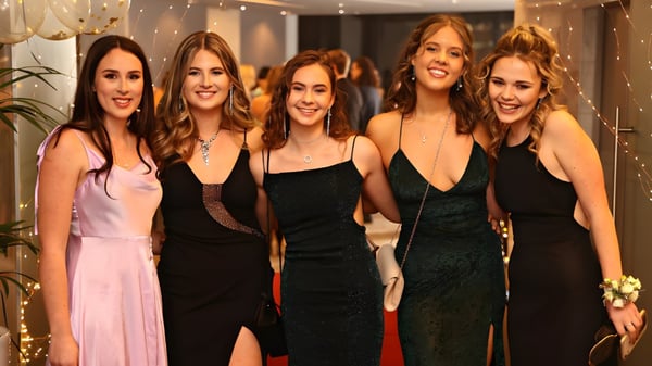 Fünf Schülerinnen des Long Bay College posieren gemeinsam in einem schwach beleuchteten Raum mit Lichterketten im Hintergrund.