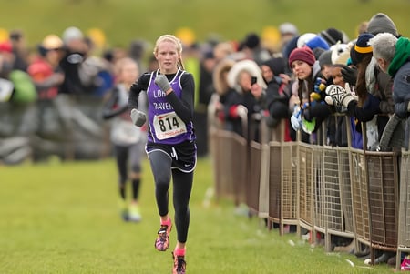 Eine Läuferin läuft auf einem Grasfeld vor Publikum auf dem Gelände der Longfields-Davidson Heights Secondary School.