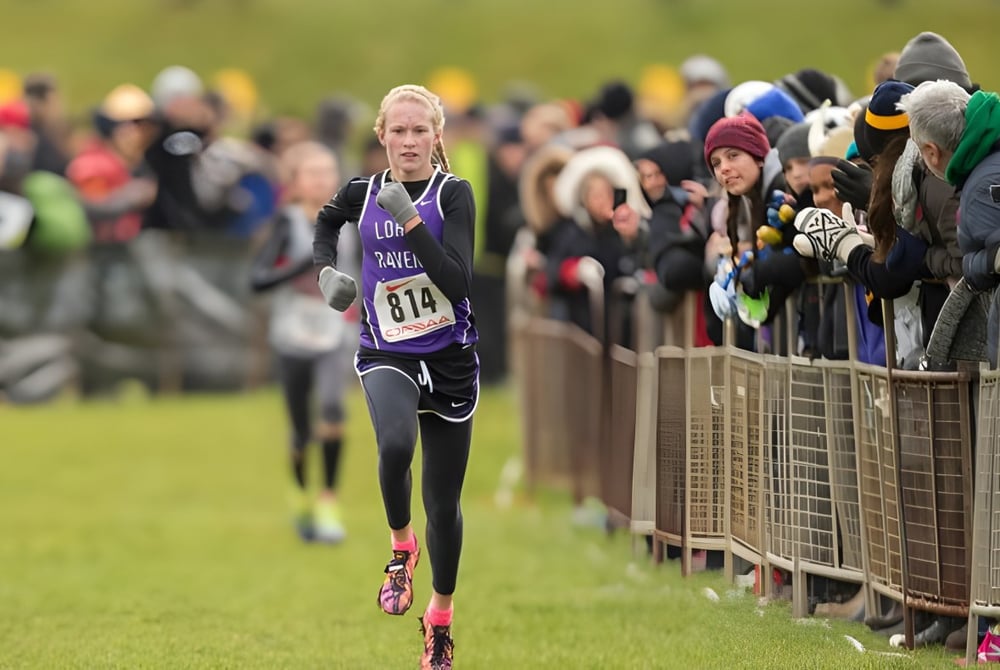 Eine Läuferin läuft auf einem Grasfeld vor Publikum auf dem Gelände der Longfields-Davidson Heights Secondary School.