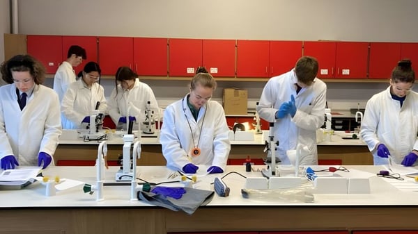 Schüler der Longridge Towers School arbeiten in weißen Laborkitteln an verschiedenen Stationen im Labor mit wissenschaftlicher Ausrüstung.