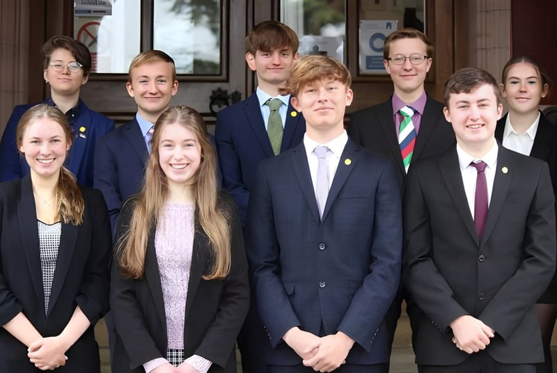 Eine Gruppe von Schülern in formeller Kleidung steht vor dem Gebäude der Longridge Towers School.
