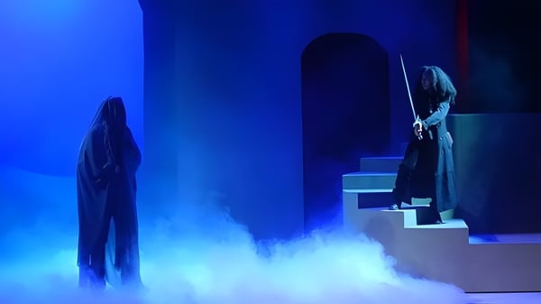 Zwei Figuren stehen auf der Bühne in einem blauen Nebel auf dem Campus der Loomis Chaffee School.