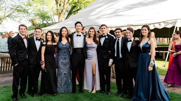 Eine Gruppe von Schülern der Loomis Chaffee School in formeller Kleidung posiert im Freien vor einem Zelt und Bäumen.