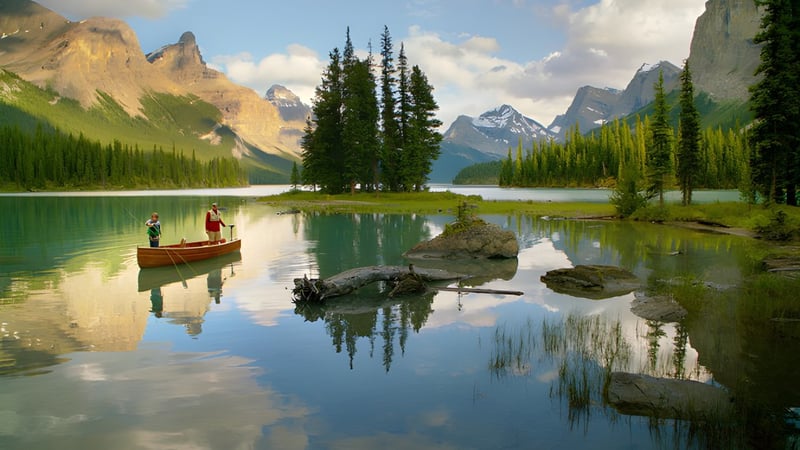 Ein ruhiger See mit einem kleinen Boot und zwei Personen spiegelt die Berge auf dem Gelände der Lord Beaverbrook High School wider.