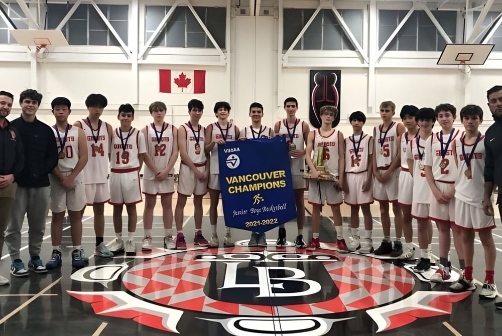 Eine Gruppe von Schülerinnen und Schülern der Lord Byng Secondary School steht in der Turnhalle mit einem Basketball- Meisterschaftsbanner.