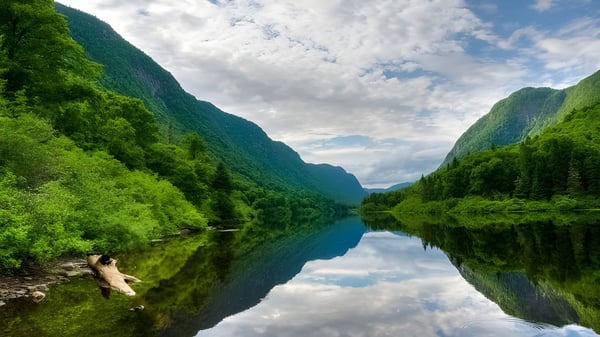 Ein stiller Bergsee mit Spiegelung von Himmel und Bäumen in der ruhigen Landschaft nahe der Lord Tweedsmuir Secondary School.