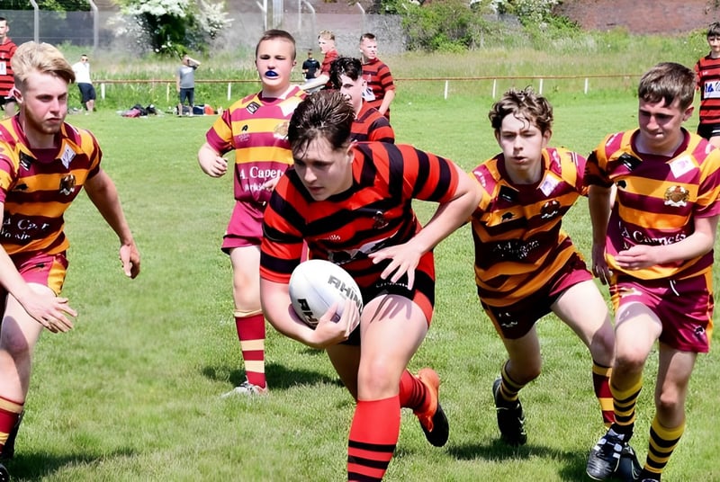 Schüler des Lord Wandsworth College spielen Rugby auf einem Spielfeld vor Zuschauern und Gebäuden.