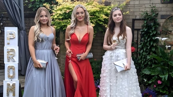 Drei Schülerinnen der Loreto Abbey Secondary School posieren vor einer Backsteinwand mit Bepflanzung im Hintergrund.