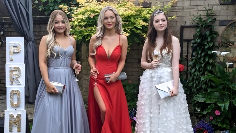 Drei Schülerinnen der Loreto Abbey Secondary School posieren vor einer Backsteinwand mit Bepflanzung im Hintergrund.