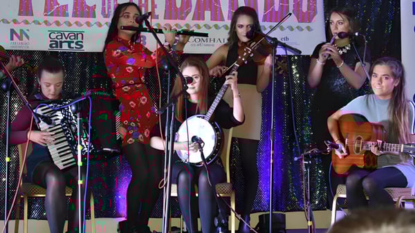 Eine Gruppe von Musikerinnen und Musikern aus dem Loreto College Cavan tritt auf der Bühne mit buntem Licht auf.