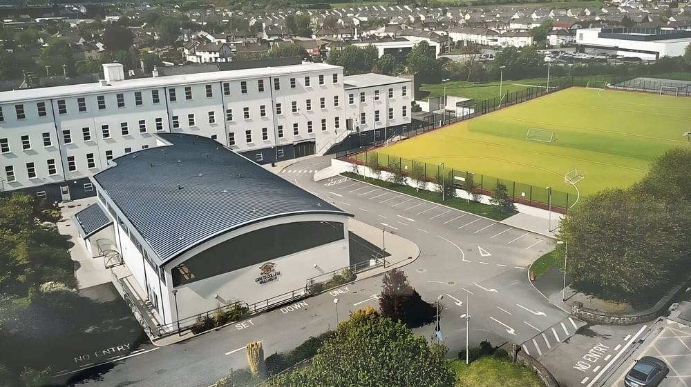 Das große mehrstöckige Gebäude mit gewölbtem Dach auf dem Gelände des Loreto College Mullingar ist von kleineren Gebäuden und einer Wiese umgeben.