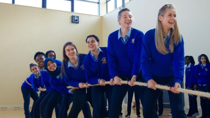 Eine Gruppe Schüler mit blauen Uniformen steht im Flur des Loreto College Mullingar und lächelt in die Kamera.