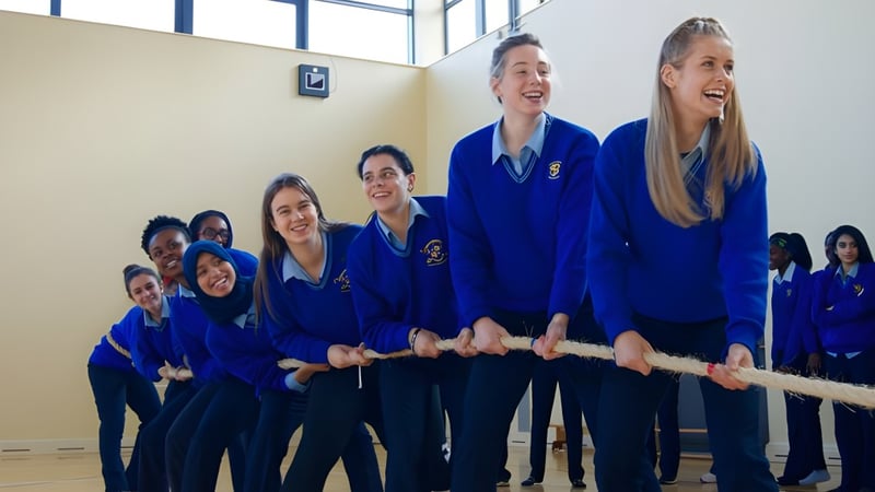Eine Gruppe Schüler in blauen Uniformen steht lächelnd zusammen im Loreto College Mullingar.