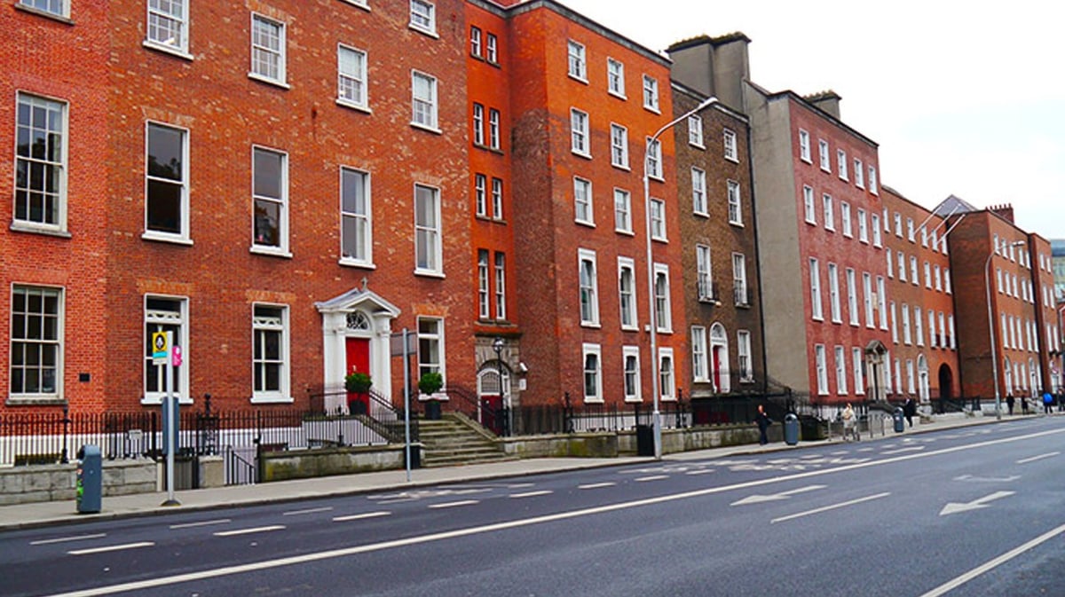 Die roten Backsteingebäude des Loreto College, St. Stephen's Green entlang einer Straße mit Fußweg.