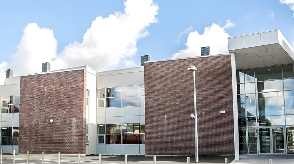 Das moderne, mehrstöckige Gebäude der Loreto Secondary School mit großen Glasfenstern vor blauem Himmel mit weißen Wolken.