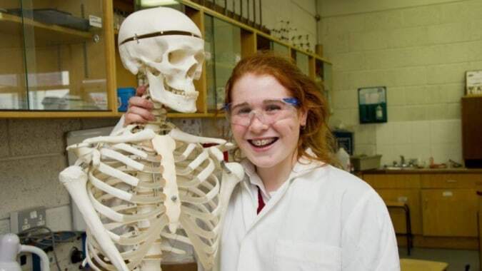 Eine Schülerin der Loreto Secondary School (Cork) steht im Labor neben einem menschlichen Skelettmodell.