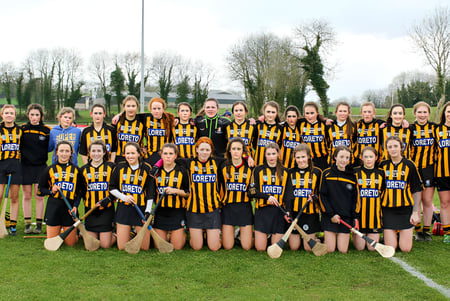 Eine große Gruppe junger Sportlerinnen steht auf dem Rasen der Loreto Secondary School vor Bäumen und Gebäuden.