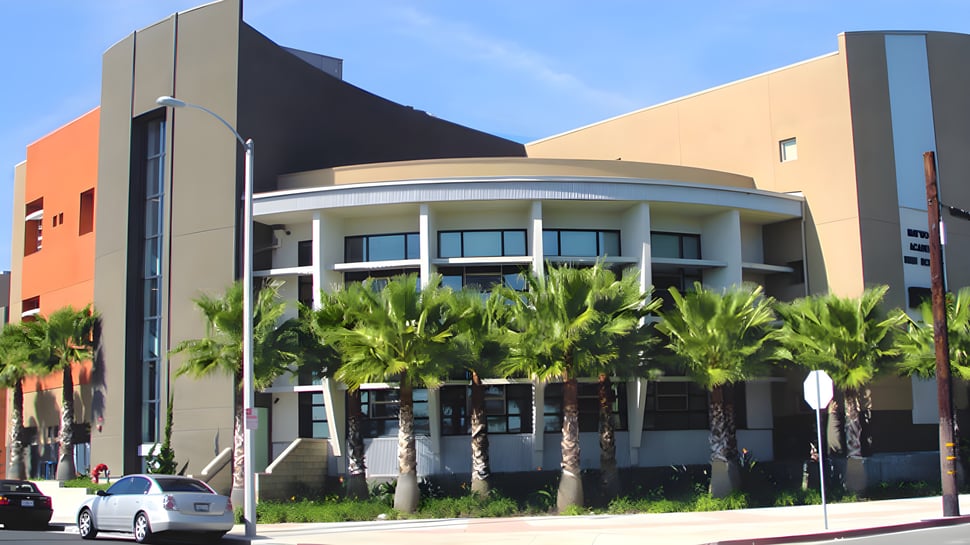 Modernes mehrstöckiges Gebäude mit geschwungener Fassade und Palmen auf dem Gelände des Los Angeles Unified School District.