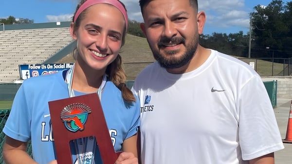 Eine Schülerin und ein Lehrer der Lourdes Academy stehen gemeinsam vor einem Sportfeld auf dem Schulgelände.