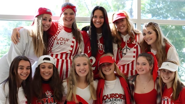 Eine Gruppe junger Schülerinnen posiert in roter und weißer Kleidung auf dem Campus der Lourdes Academy.