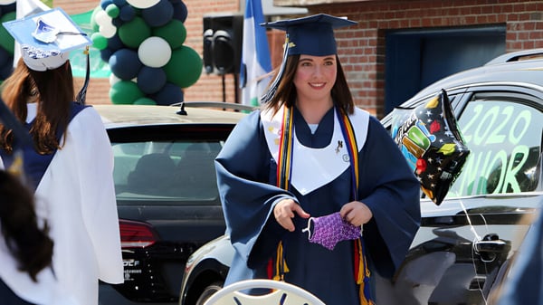 Eine Schülerin der Lowell Catholic High School trägt eine Abschlussrobe und hält ein Diplom in der Hand.