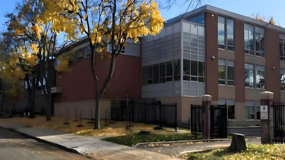 Das moderne Gebäude des Lower Canada College ist von Bäumen mit gelben Herbstblättern umgeben und zeigt einen gepflasterten Weg im Vordergrund.