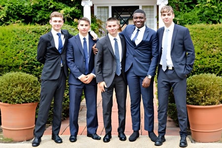 Eine Gruppe von Schülern der Luckley House School steht zusammen in einem gepflegten Garten mit Töpfen und Hecken.