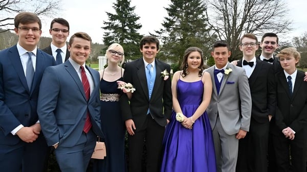 Eine Gruppe Schülerinnen und Schüler der Luckley House School steht formell gekleidet vor Bäumen auf einer Rasenfläche.