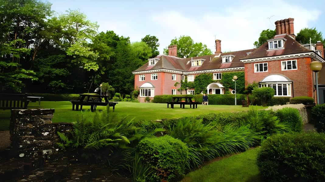 Das Herrenhaus mit rotem Backstein auf dem Gelände der Luckley House School ist von einem üppigen Garten umgeben.