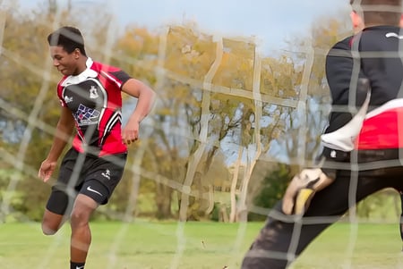 Ein Mann in einem rot-schwarzen Trikot läuft über ein grünes Feld auf dem Gelände der Lucton School.