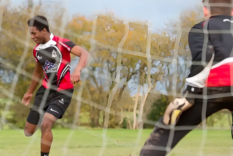 Ein Mann in einem rot-schwarzen Trikot läuft über ein grünes Feld auf dem Gelände der Lucton School.
