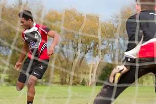 Ein männlicher Schüler der Lucton School läuft auf einem Grasfeld mit Bäumen und Gebäuden im Hintergrund.