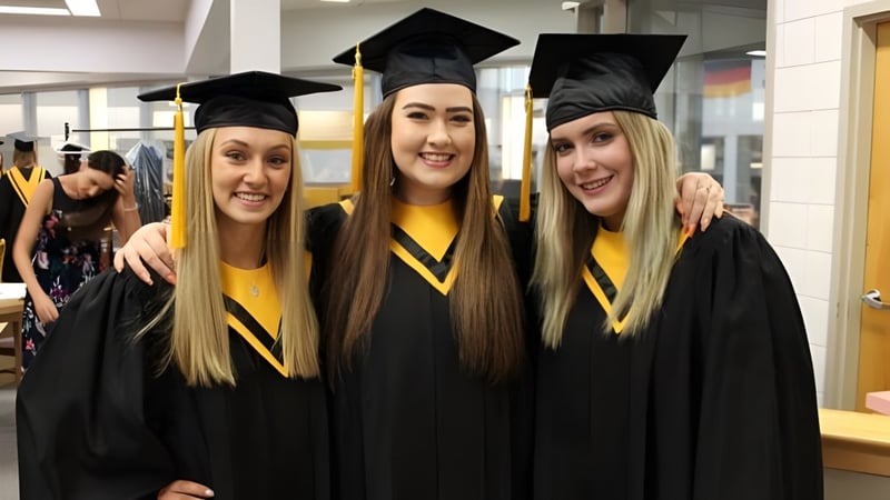 Drei Schülerinnen in Abschlusskleidung posieren für ein Foto auf dem Gelände der Luther College High School.