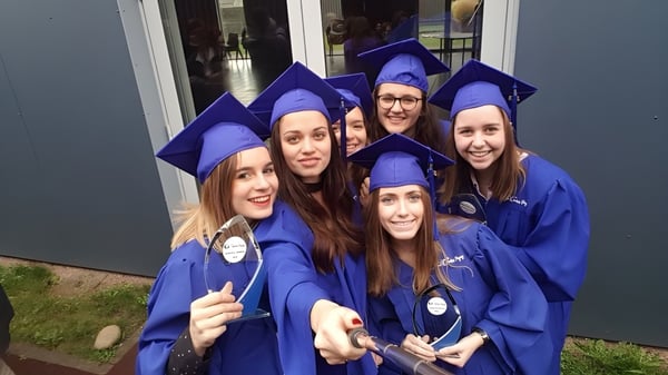 Eine Gruppe junger Frauen in blauen Abschlussroben posiert vor einem Gebäude auf dem Campus des Lycée Charles Péguy.