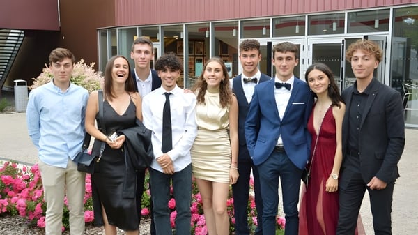 Eine Gruppe Schülerinnen und Schüler des Lycée Charles Péguy steht in formeller Kleidung vor einem rosa Gebäude.