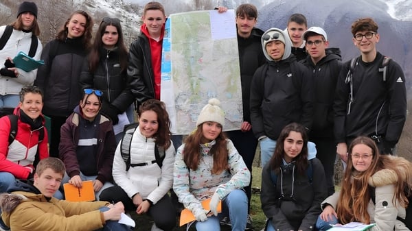 Eine Gruppe von Schülerinnen und Schülern des Lycée Charles Péguy steht draußen in einer verschneiten Berglandschaft.