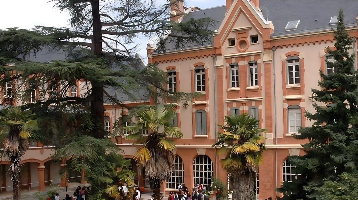 Das Gebäude des Lycée Gabriel Fauré zeigt ein großes Haus mit rotem Ziegeldach und Palmen im Vordergrund.