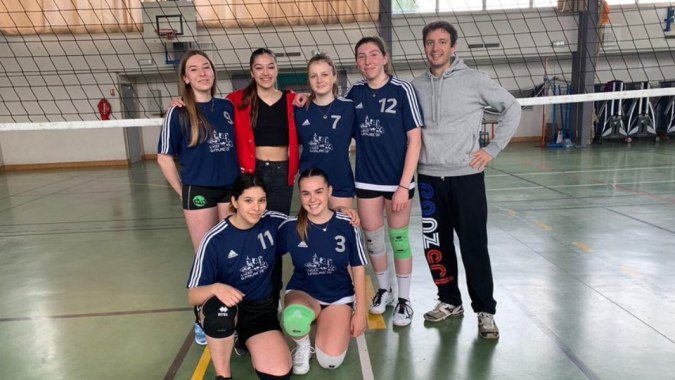 Eine Gruppe junger Volleyballspielerinnen posiert in der Sporthalle des Lycée Gabriel Fauré vor einem Basketballkorb.