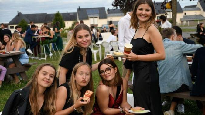 Schülerinnen des Lycée Immaculée Jean Paul II versammeln sich draußen bei einer Feier mit Essen und Getränken.