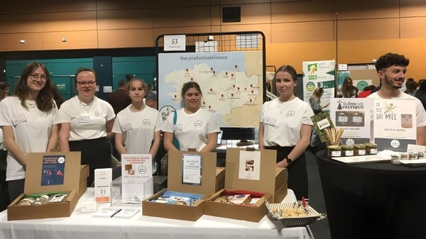 Schüler des Lycée Immaculée Jean Paul II präsentieren an einem Tisch verschiedene Produkte und Informationsmaterialien.