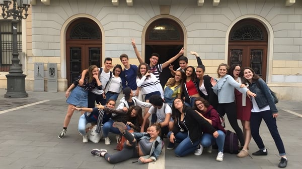 Eine Gruppe von Schülerinnen posiert vor einem verzierten, gewölbten Gebäude auf dem Campus des Lycée Jean Brito.
