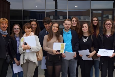 Eine Gruppe Schüler steht vor dem Glasgebäude auf dem Campus des Lycée Jean Brito und hält Papiere in den Händen.